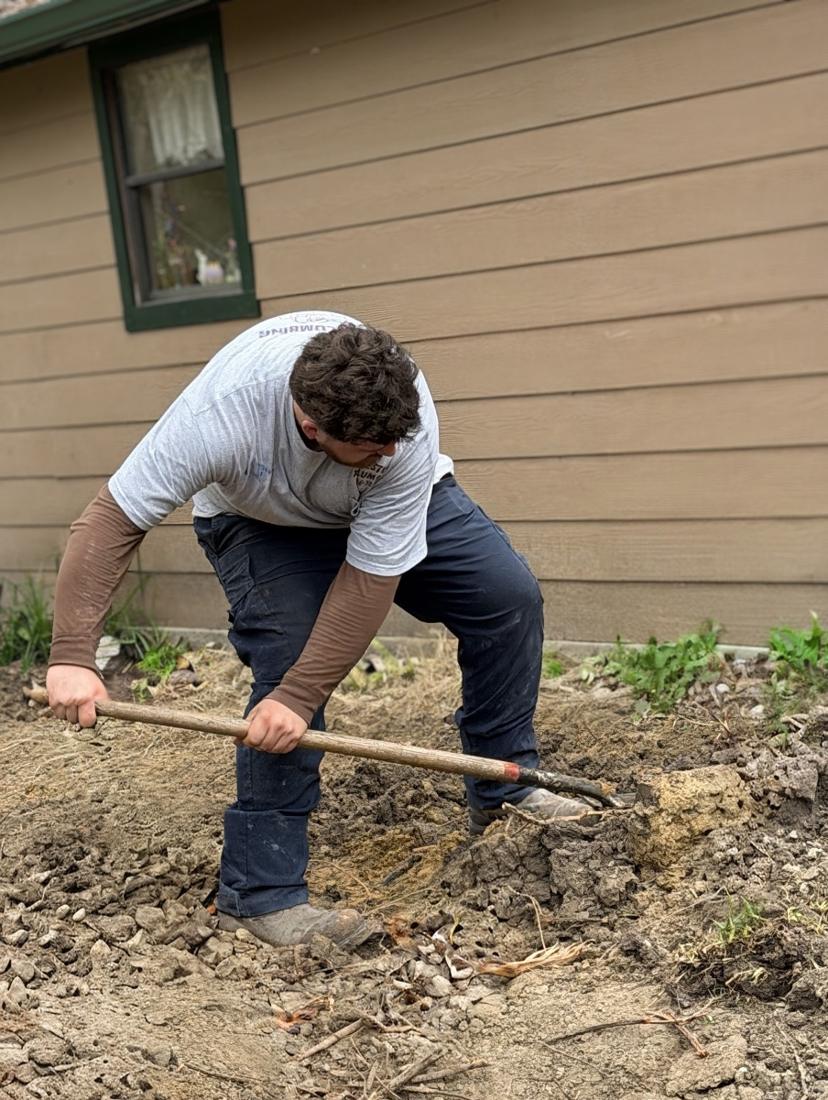Tech digging along the side of a house