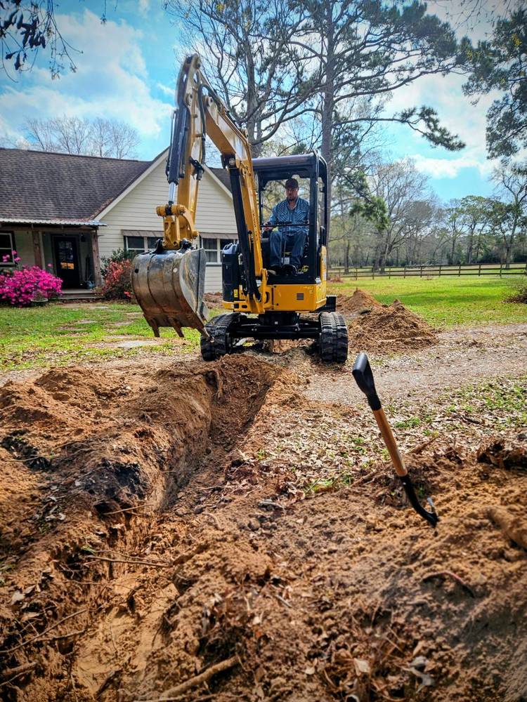 Mini excavator digging a trench for a new line beside a house