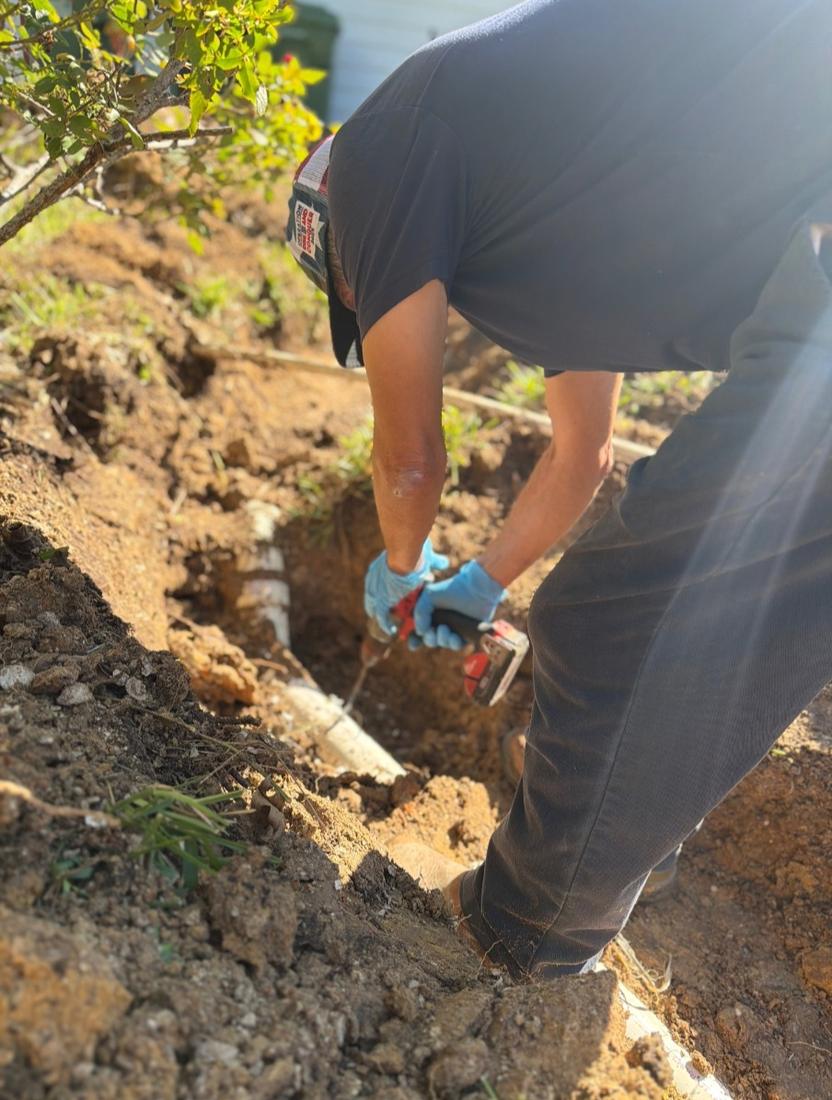 Tech repairing a buried PVC line in an open trench